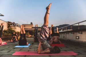 People practicing yoga on mats outdoors during sunset, focusing on wellness.